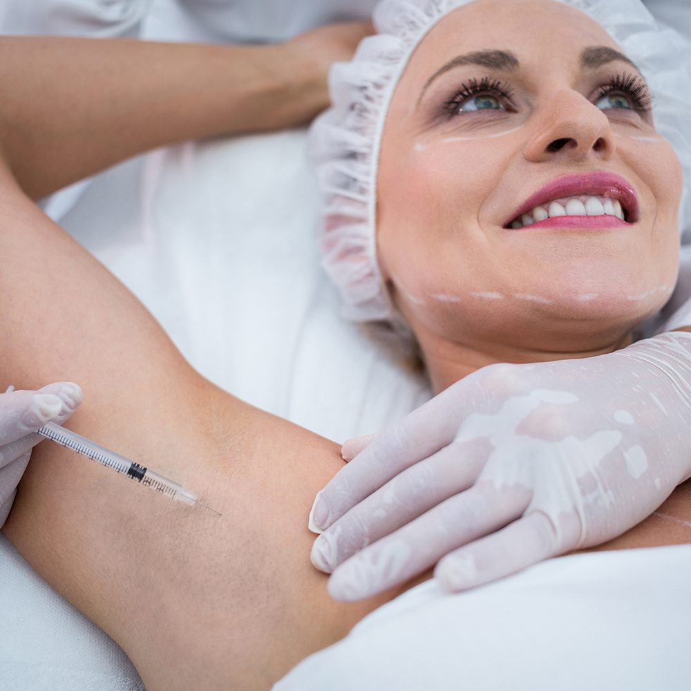 Close-up of doctor injecting woman on her arm pits