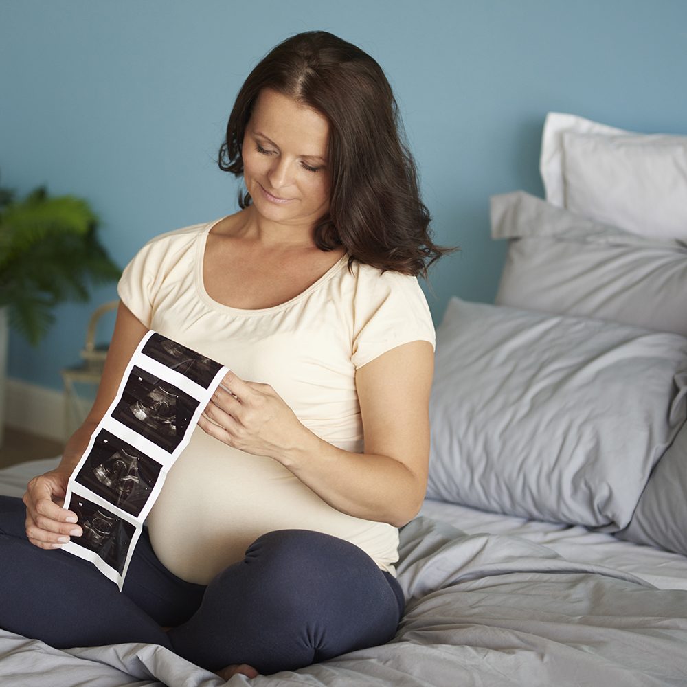 Pregnant woman browsing ultrasound image of her baby